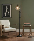 Tall Industrial LED Floor Lamp With Adjustable Head And Rustic Glass Teardrop Shade, Black Finish, beside chair and table in living room