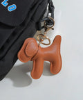 Premium Faux Leather Dog Bag Charm With Sturdy Metal Keyring attached to a black backpack, featuring a cute brown dog design.