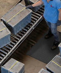 Built Different And Tough As Nails Anti Fatigue Mat With Heavy Duty Diamond Texture For Standing All Day Without Breaking A Sweat Grease And Oil Resistant Commercial Closed Cell Foam Ergonomic Work Pad In Black Three By Five Feet under worker with boxes on conveyor.