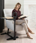 Woman using Adjustable Bamboo Tray Table With Ergonomic Safety Handle And Stand For Couch, reading book by fireplace, in living room