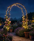 7.2 Ft Outdoor Steel Garden Arch Arbor With Stakes illuminated at night, surrounded by climbing roses and potted flowers