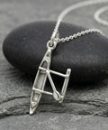 Outrigger Canoe Charm Necklace For Women Sterling Silver Dainty Handmade Ocean Boat Pendant displayed on stone