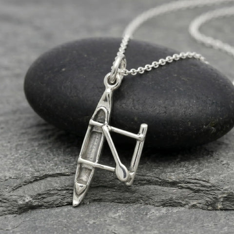 Outrigger Canoe Charm Necklace For Women Sterling Silver Dainty Handmade Ocean Boat Pendant displayed on stone