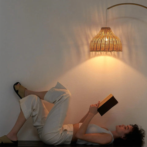 Person reading under Lark Arc Floor Lamp With Hanging Wicker Shade Brass Tall Standing Light For Living Room And Office Perfect For Reading And Cozy Boho Chic Vibe Decor For Any Space.
