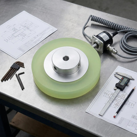 Beefy Rotary Encoder Meter Wheel With 6mm Aperture For Marking Machines And Inkjet Printers on a workbench with tools and drawings