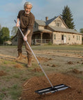 Man using Roller Lawn Leveling Rake With 83.9 Inch Adjustable Handle, 36 Inch By 10 Inch Stainless Steel Yard Leveler on dirt yard