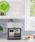La Specialista Arte Espresso Machine Conical Burr Grinder Eight Grind Settings on kitchen counter with cups and pastries.