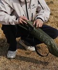 Person holding Ultra Lightweight Outdoor Camping Backrest Chair With Carry Bag For Park Vibes And Beach Days in grass.
