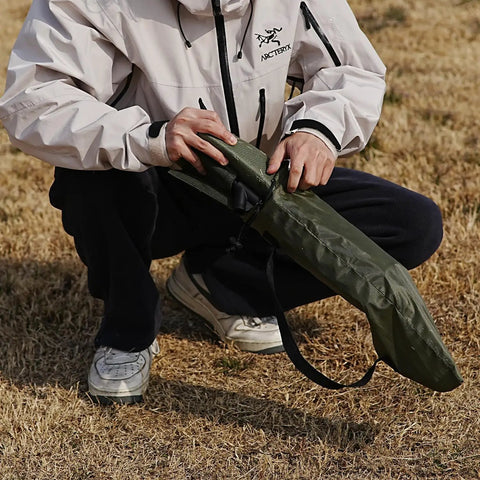 Person holding Ultra Lightweight Outdoor Camping Backrest Chair With Carry Bag For Park Vibes And Beach Days in grass.