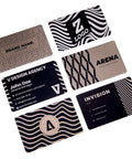 Front view of six black metal business-card blanks for laser engraving with geometric and wavy patterns.