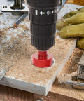 Diamond hole saw drill bit (red) attached to a drill chuck drilling into wood with sawdust.