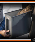 Close-up of heavy duty pellet storage bin in use, featuring airtight lid and wood chips for grilling. Level Up Your Smoke Game With This Heavy Duty Pellet Storage Bin Featuring A Rugged Locking Lid And Smart Stackable Design To Keep Wood Chips Bone Dry For Peak Grilling Days.