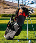 Golf Accessory Bag Organizer With Carabiner Clip attached to a golf bag on a course with balls on the grass