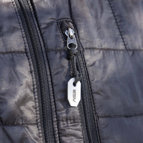 Close-up of black jacket zipper with ASR logo puller, showcasing durable material and stitching.