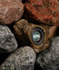 Alt Tag: 3-Pack 1.5-Watt Rock Lights With Low-Voltage 20-Watt Transformer For Landscape Lighting Ponds And Water Features Submersible In Or Out Of Water 2800K Warm White Emitting 70 Lumens Each With Photocell Control nestled among natural rocks