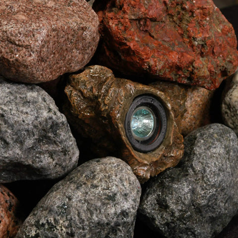 Alt Tag: 3-Pack 1.5-Watt Rock Lights With Low-Voltage 20-Watt Transformer For Landscape Lighting Ponds And Water Features Submersible In Or Out Of Water 2800K Warm White Emitting 70 Lumens Each With Photocell Control nestled among natural rocks