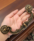 Four Piece 150mm Center Drawer Pull Handles in Zinc Alloy Rustic Vintage Style with antique yellow bronze finish held in hand