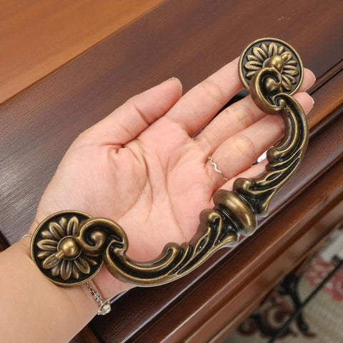 Four Piece 150mm Center Drawer Pull Handles in Zinc Alloy Rustic Vintage Style with antique yellow bronze finish held in hand