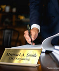 Custom Engraved Brushed Brass Office Door Name Plate And Personalized Desk Sign Featuring Sleek Metal Construction Easy Cubicle Wall Or Adhesive Mount For Bosses Crushing It Daily on a desk.