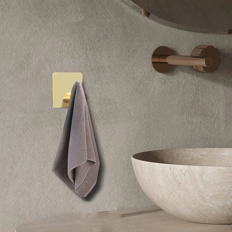 Gold Heavy Duty Self Adhesive Hooks 4 Pack Wall Mounted For Towel Key Coat Hat Robe Clothes Waterproof Aluminum No Drilling Required Ideal For Bathroom And Kitchen, showing a hook with a hanging towel.