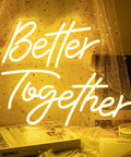 Better Together Neon Sign LED Light for Weddings and Home Bar Decor glowing warm white on a table with books