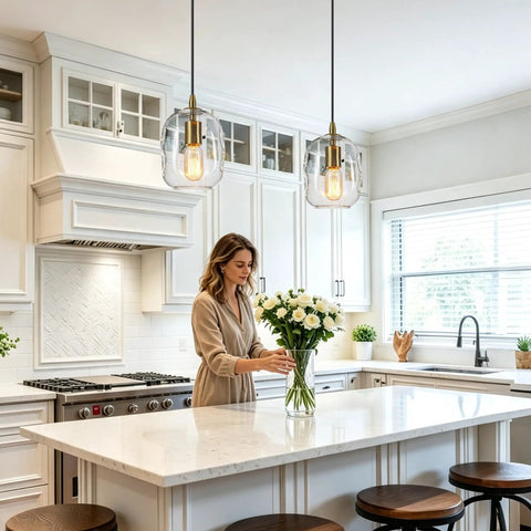 Pendant Lights Kitchen Island, Hand-Blown Clear Glass Brass Gold 9 Inch H illuminating a kitchen with a woman arranging flowers.