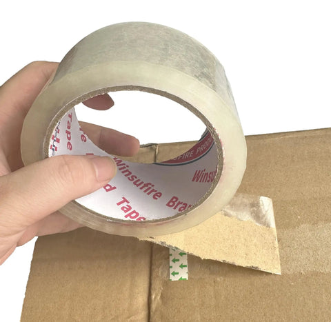 Hand holding heavy duty packing tape for shipping and moving, 1.88 inch wide by 65 yards per roll, sealing cardboard box