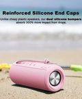 Pink outdoor portable Bluetooth boombox speaker waterproof shown on sandy beach with dual silicone end caps.