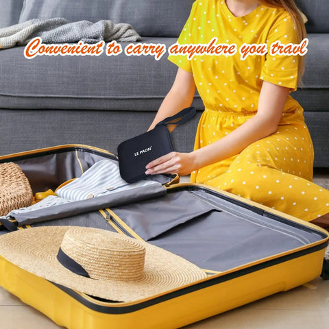 Person packing Grab And Go Portable Sewing Kit With Case For Home And Travel into a suitcase, next to a hat and clothing.