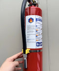 Four Pack Five Lb Abc Dry Chemical Fire Extinguisher Set Featuring No Fuss Quick Release Pin on display with user holding it.