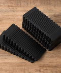 Rock Solid Black Rubber Wedge Shims For Furniture Leveling Hella Sturdy Anti Slip Wobble Pads stacked on a wooden surface.