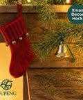 Red Christmas stocking with bells hanging on wooden ledge next to evergreen branch with silver bell decoration.
