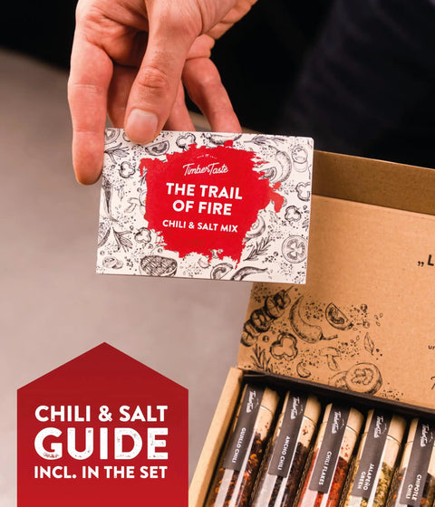 Hand holding 'The Trail of Fire' chili and salt mix from Salt And Chili Gift Kit For Men, 5 Gourmet Sea Salts And 5 Hot Chili Varieties