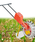 Rugged Garden Push Seeder Hand Push Manual Seeder Walk Behind Planter in a field with rows of young crop plants