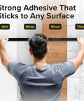Person testing magnetic tape's adhesive strength on wall, metal, wood, and tiles. Magnetic Tape With Adhesive Backing 10 Feet Long By Half Inch Wide DIY Friendly Lightweight Magnetic Strip For Crafts And Organization Easy To Cut And Mount On Fridges And Whiteboards That Sticks For Light Duty Labels And Mounts