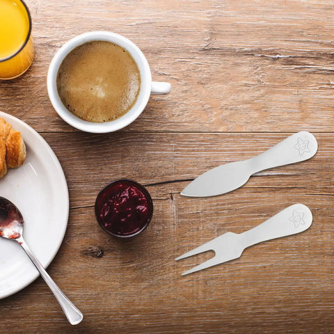 Cheese Knife And Butter Fork Set, Stainless Steel 5 Piece on wooden table beside coffee and jam, ideal for outdoor dining.