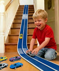 Child playing with 15-Foot Build-Your-Own Creative Race Track Set For Kids With Bold Blue And White Track Toy Cars on staircase