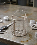 Hella Solid Stainless Steel Ultrasonic Cleaner Basket With Swinging Handle And Fine Mesh Grid Drop Right In For Jewelry Lab Parts Cleaning Bad Boy Universal Fit Heavy Duty Precision Filter Basket Tray on a workbench.