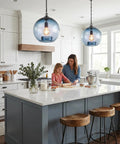 CASAMOTION Modern Farmhouse Blue Glass Globe Pendant Light 11" Dia hanging above a mother and daughter in a stylish kitchen.