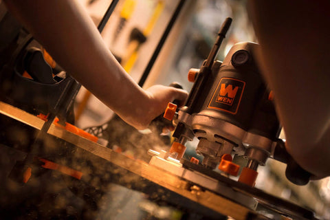Person using Rock-Solid 15 Amp Variable Speed Plunge Router Kit With Carrying Case And Edge Guide on woodworking project.