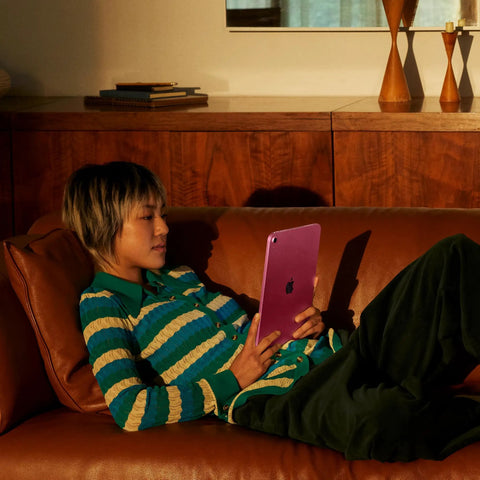 Person relaxing on a sofa using 11 Inch iPad With A16 Chip, Liquid Retina Display, 128GB Storage, WiFi 6, in silver color
