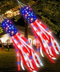 Patriotic 2 Pack 40 Inch American Flag Windsocks With Lights For Fourth Of July Memorial Day Independence Day Decor Red White Blue Stars And Stripes Hanging Windsocks glowing in a garden at night.