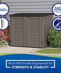 34 Cu Ft Horizontal Resin Storage Shed With Floor Included For Outdoor Use Weatherproof And Lockable Fits Small To Medium Trash Cans Generators And Garden Tools Stoney Black next to a shrub with wall backdrop.