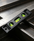 Magnetic Torpedo Level 6 Inch, 3 Bubble Spirit Measuring Tool placed on steel surface with measuring ruler.