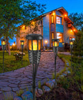 Front view of Four Pack Outdoor Tiki Torches With Realistic Flickering Flame Waterproof Bamboo Handwoven Rattan Design In Black lighting a garden path