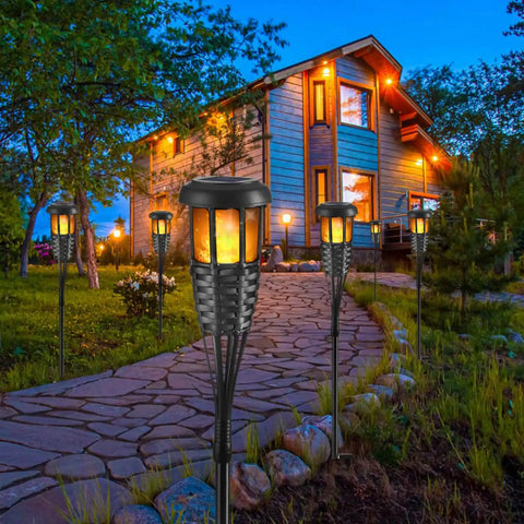 Front view of Four Pack Outdoor Tiki Torches With Realistic Flickering Flame Waterproof Bamboo Handwoven Rattan Design In Black lighting a garden path