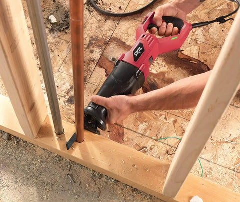 Person using Beefy 9 Amp Reciprocating Saw For Tough Demolition Jobs With Tool Free Blade Change, cutting through copper pipe