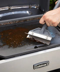 Beast Mode Heavy Duty Griddle Scraper With 6 Inch Stainless Steel Blade Ergonomic Handle And Splash Guard cleaning a grill