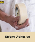 Hand holding Contractor Grade Masking Tape 0.94 Inch By 60.1 Yard Pack Of 36 Rolls, High Adhesion Painter Tape