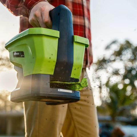 Person using 20-Volt Cordless Handheld Seed And Fertilizer Spreader For Yard Work With Adjustable Spreading Rate Dial outdoors